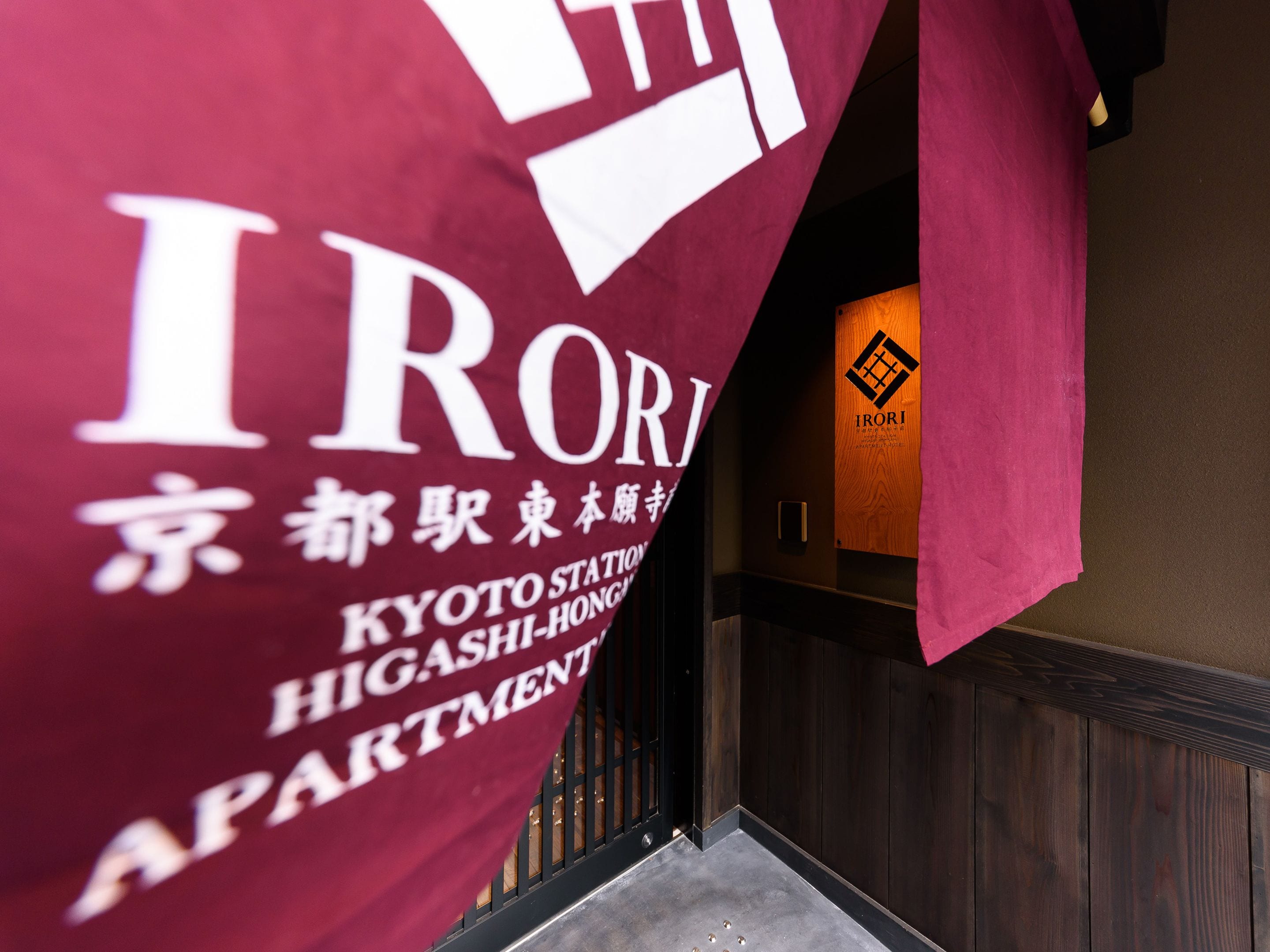A maroon banner with white text reading "IRORI KYOTO STATION HIGASHIHONGUYA APARTMENTS".