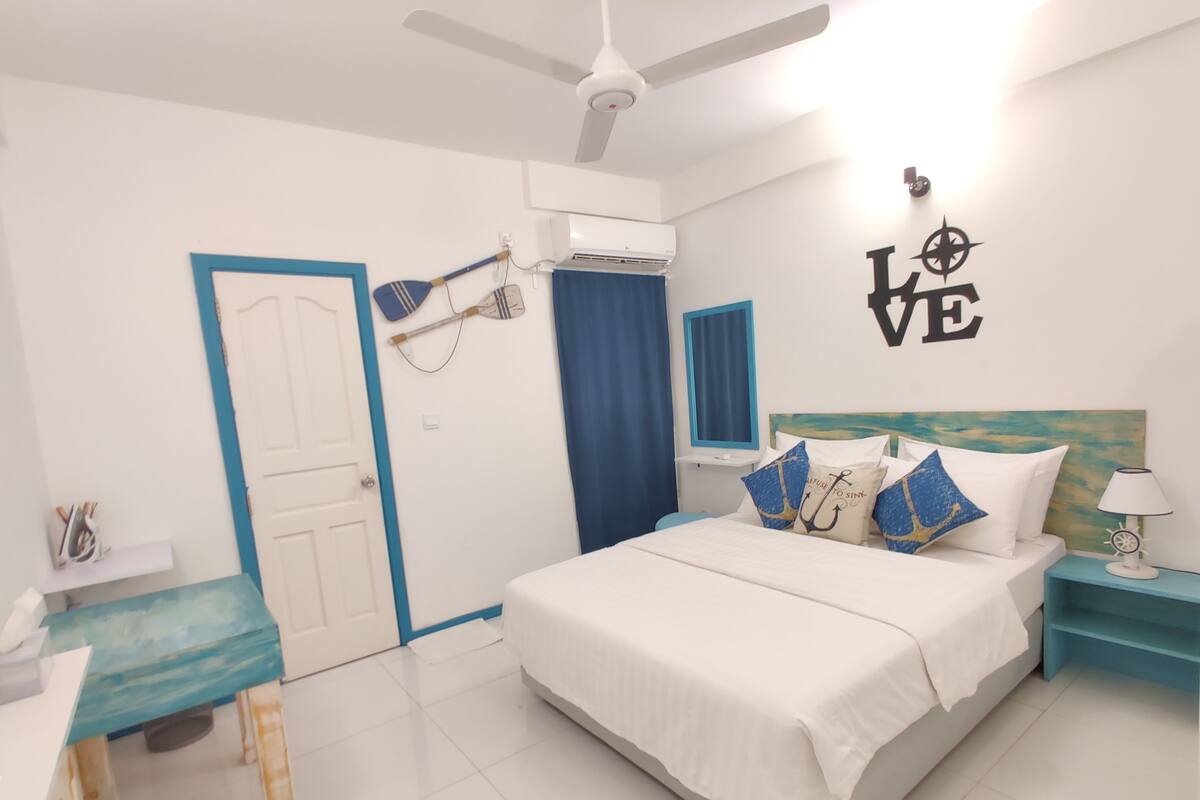 A modern bedroom with a bed, a desk, and a ceiling fan.
