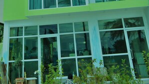 A multi-story building with large windows and a green facade. - The Aquzz (Hulhumalé)