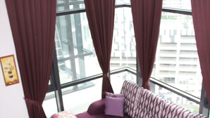 A modern living room with a purple sofa, a patterned rug, and large windows with curtains. - Eclipse Residence Duplex (Cyberjaya)