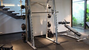 A gym with weightlifting equipment, a bench, and a staircase. - Eclipse Residence Duplex (Cyberjaya)