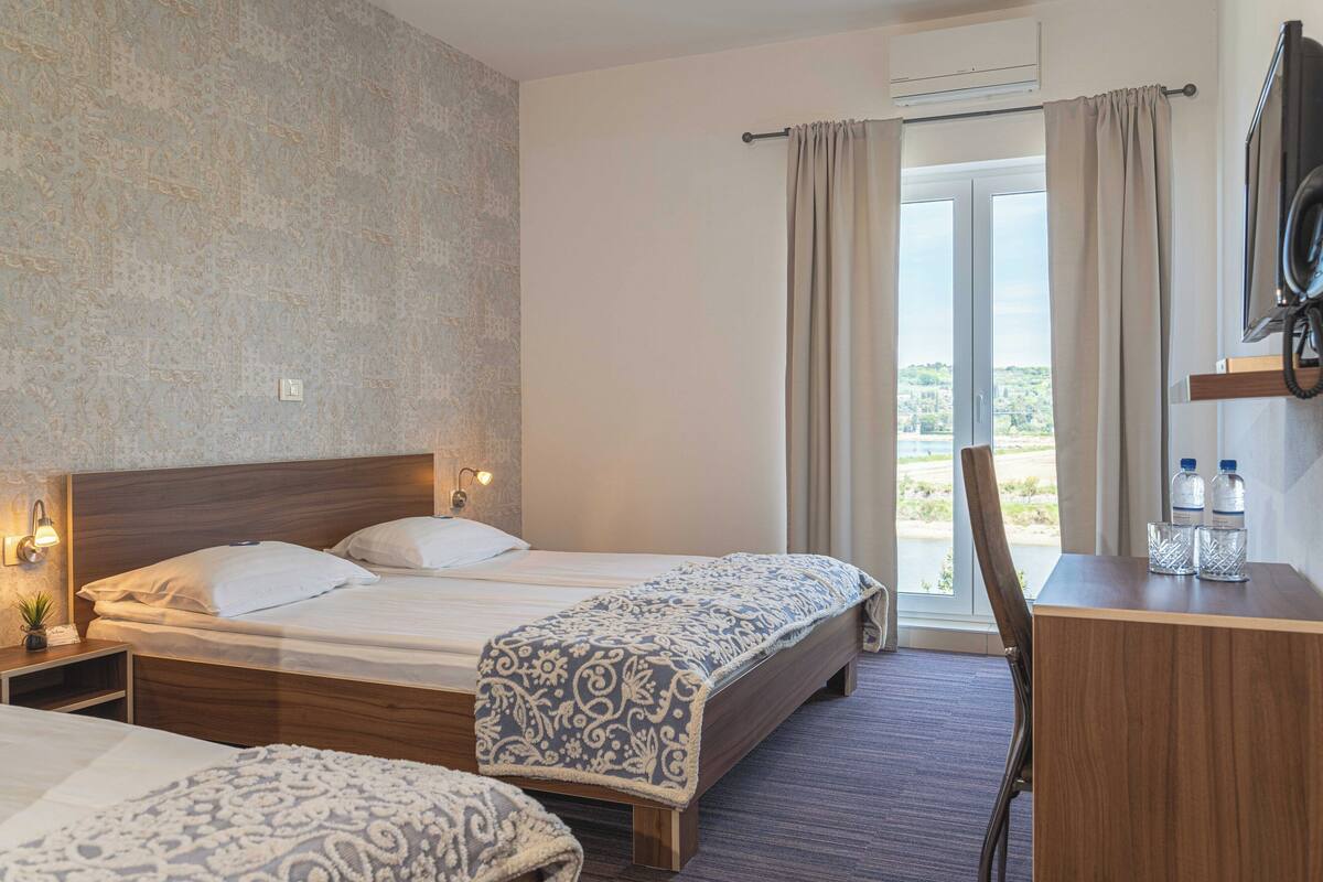 A hotel room with two beds, a desk, and a chair.