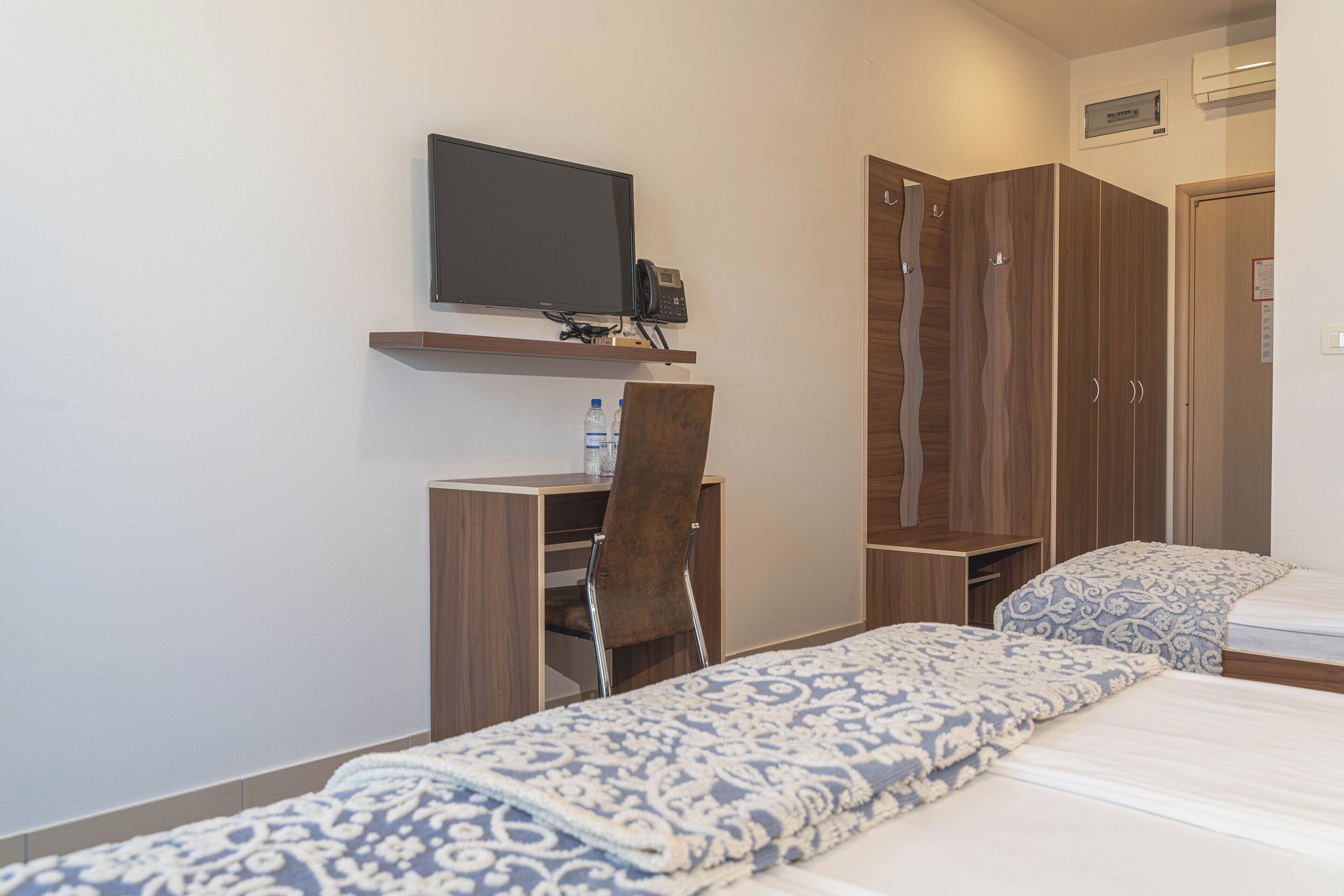 Een hotelkamer met een bed, een bureau met stoel, een televisie en een kledingkast.