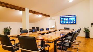 Een vergaderruimte met een lange tafel, zwarte stoelen en een wand waarop pictogrammen worden weergegeven.