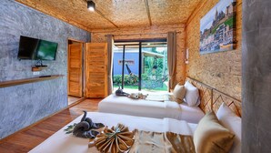 Une chambre avec deux lits, une télévision et une grande fenêtre donnant sur un paysage verdoyant.
