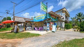A restaurant with outdoor seating, a signboard for a transport tour, and a building with a balcony. - Baan Check In (Ko Lanta)