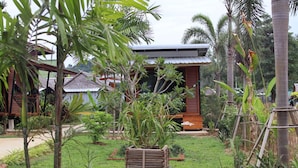 Un complexe hôtelier tropical doté de chalets en bois, d’une végétation luxuriante et d’un jardin bien entretenu.