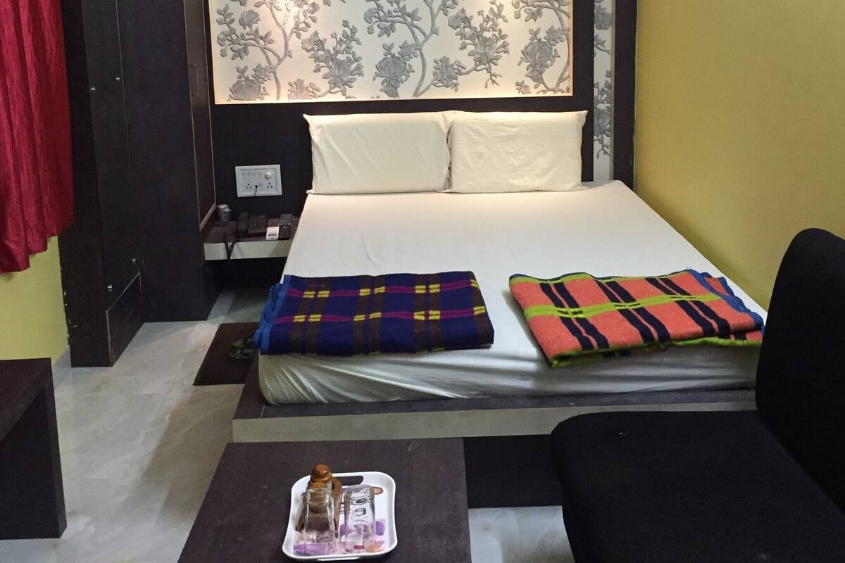 A hotel room with a bed, bedside table, and a nightstand.