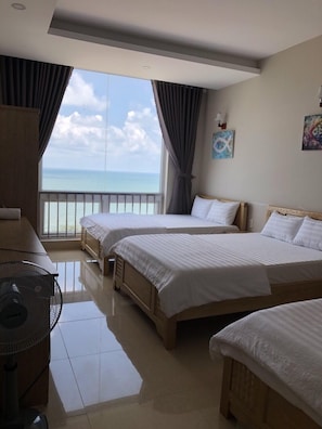 Een hotelkamer met twee bedden, een bureau en uitzicht op de oceaan.