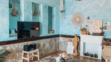 Una sala de estar con televisor, sofás con estampado floral, una mesita de centro y una chimenea.