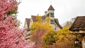 Een traditioneel huis met een stenen muur en een toren, omringd door herfstkleuren.