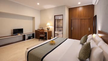 Una camera d'albergo con un letto grande, una scrivania con una lampada, una TV e un armadio.