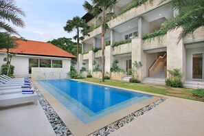 Una piscina amb gandules, una escala i un edifici amb balcons.