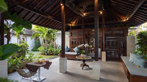 Un espace extérieur abrité, doté d’un plafond en bois, de sièges et de plantes en pot.