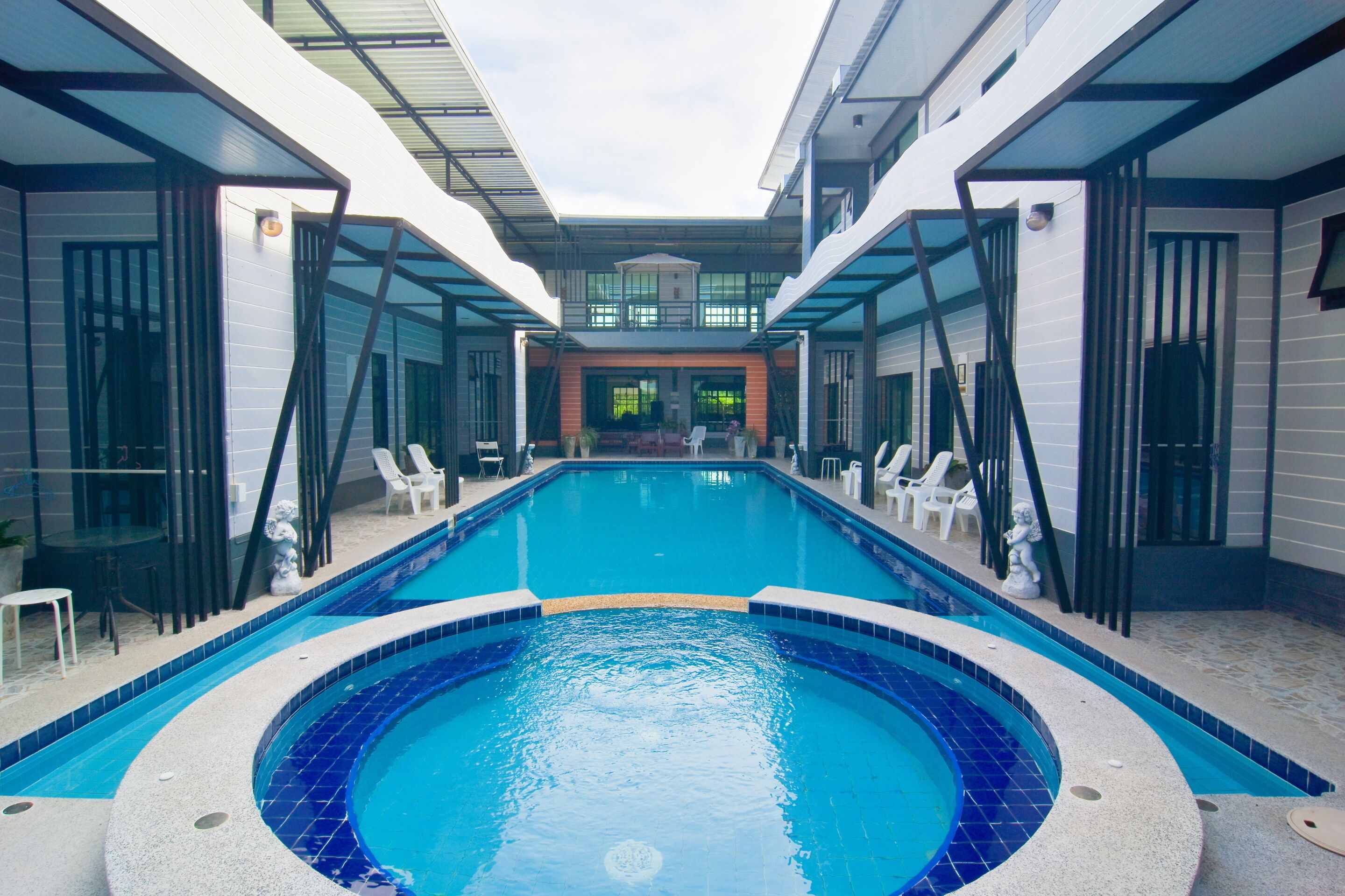 A modern indoor swimming pool with clear blue water, surrounded by lounge chairs and a glass-enclosed area.