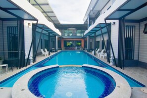 Una piscina interior moderna con agua azul cristalina, rodeada de sillones de descanso y una zona acristalada.