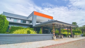 A modern building with a covered outdoor area, surrounded by greenery and a paved walkway. - OYO 500 Cordelia Resort Samroiyod (Sam Roi Yot)