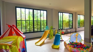 A spacious indoor play area with large windows, a slide, a ball pit, and a tent. - OYO 500 Cordelia Resort Samroiyod (Sam Roi Yot)