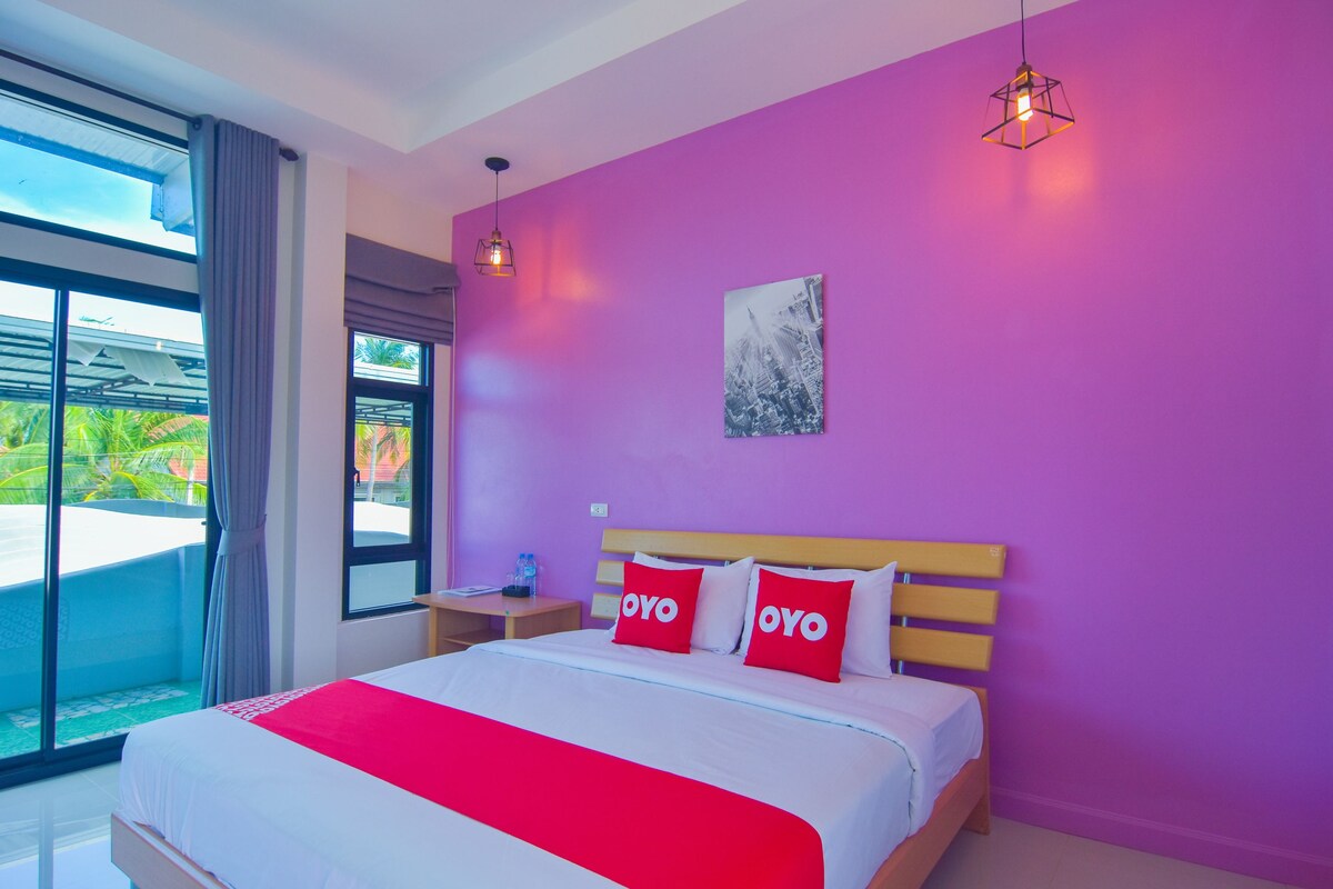 Habitación de hotel con cama, mesita de noche, ventana con cortinas y vistas al exterior.