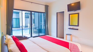 A hotel room with a large bed, a TV, a small table, and a view of a pool and outdoor seating. - OYO 500 Cordelia Resort Samroiyod (Sam Roi Yot)