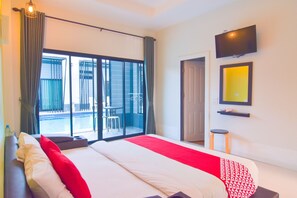 A hotel room with a bed, a TV, a small table, and a view of a pool and outdoor seating. - OYO 500 Cordelia Resort Samroiyod (Sam Roi Yot)