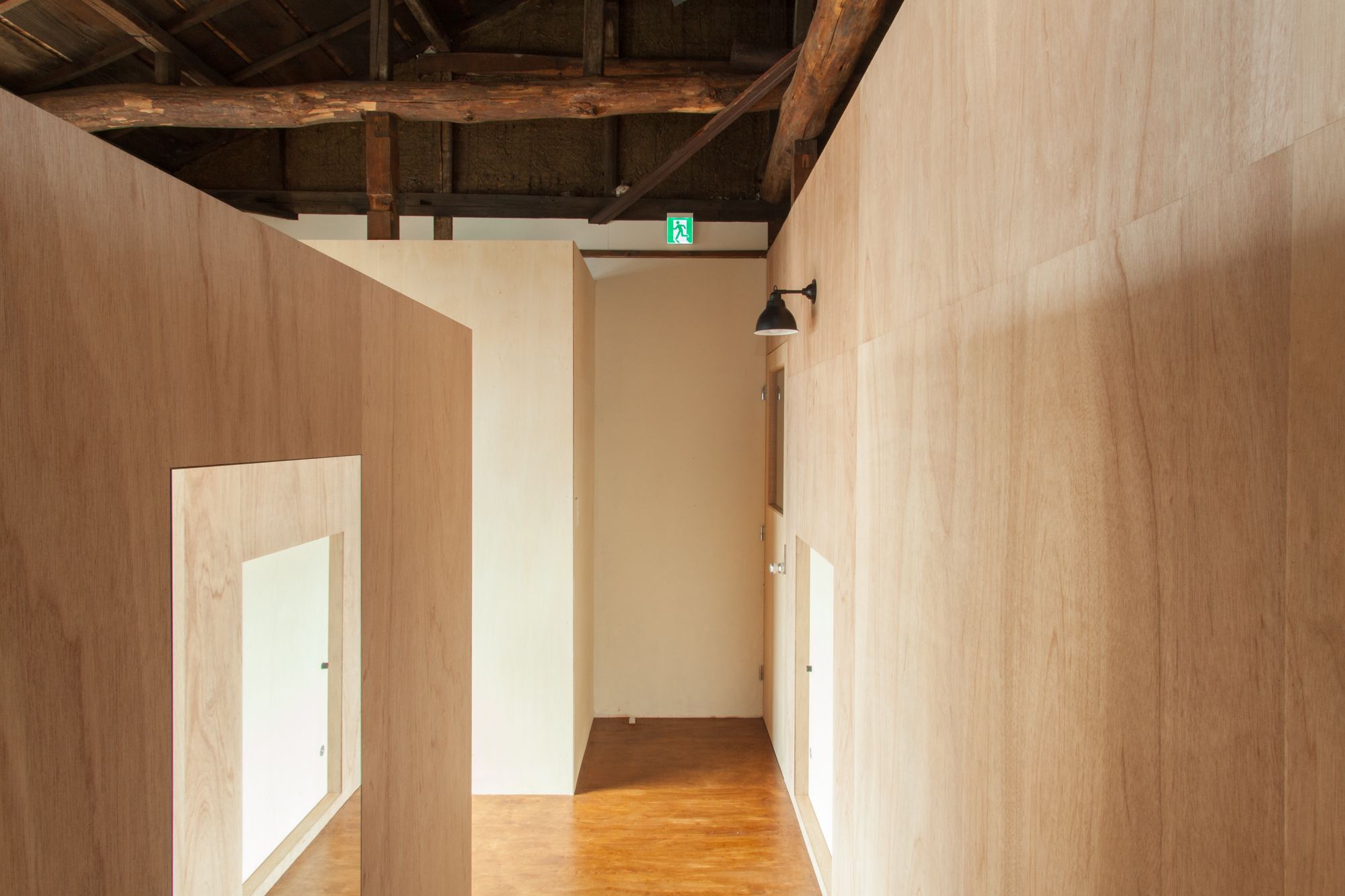 A hallway with wooden walls and a wooden floor, leading to a room with a door.