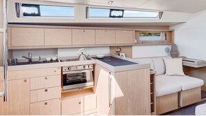 A compact kitchen with a built-in oven, a sink, and a small countertop. There is a window above the sink and a picture frame on the wall. - Discover Sailing Asia - Hong Kong (Sai Kung)