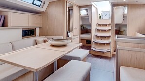 A modern RV interior with a dining area, seating, and storage cabinets. - Discover Sailing Asia - Hong Kong (Sai Kung)