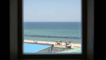 Uitzicht op een strand met heldere lucht, een zandstrand en een kalme zee. Er staan twee houten constructies op het strand, mogelijk zitgedeeltes.