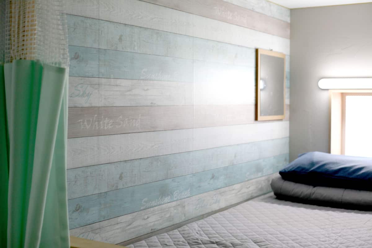 Ein Schlafzimmer mit einem Bett, einem Fenster und einer Wand mit Holzpaneelen.
