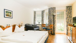 A hotel room with a large bed, a desk, a chair, and a television. - Hotel Zwei Länder (Apolda)
