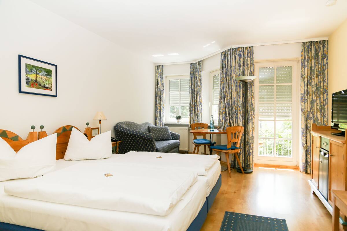 A hotel room with a large bed, a desk, a chair, and a television.