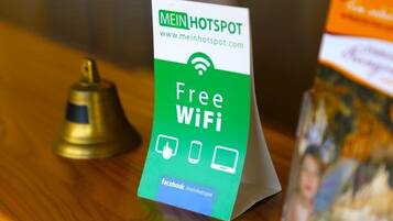 A sign offering free WiFi, a bell, and a Facebook link on a wooden surface.