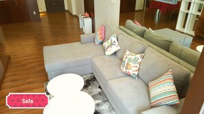 A modern living room with a grey sectional sofa, a white coffee table, and patterned throw pillows.
