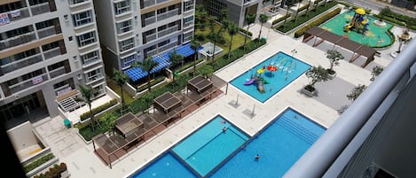Un immeuble résidentiel doté de nombreux balcons, d’une piscine et d’un espace de jeux pour enfants.