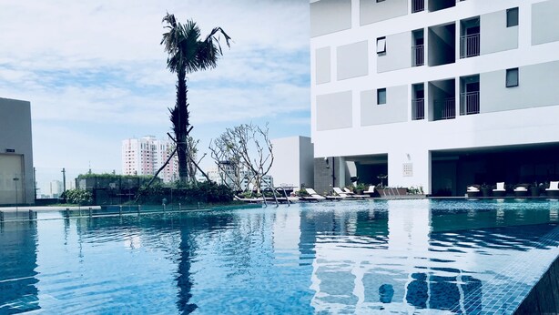 Ein Swimmingpool mit klarem, blauem Wasser, umgeben von modernen Gebäuden und einer Palme.