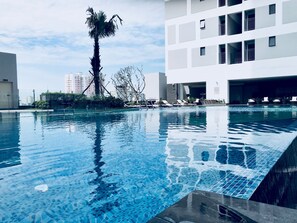 Ein Swimmingpool mit klarem, blauem Wasser, umgeben von modernen Gebäuden und einer Palme.