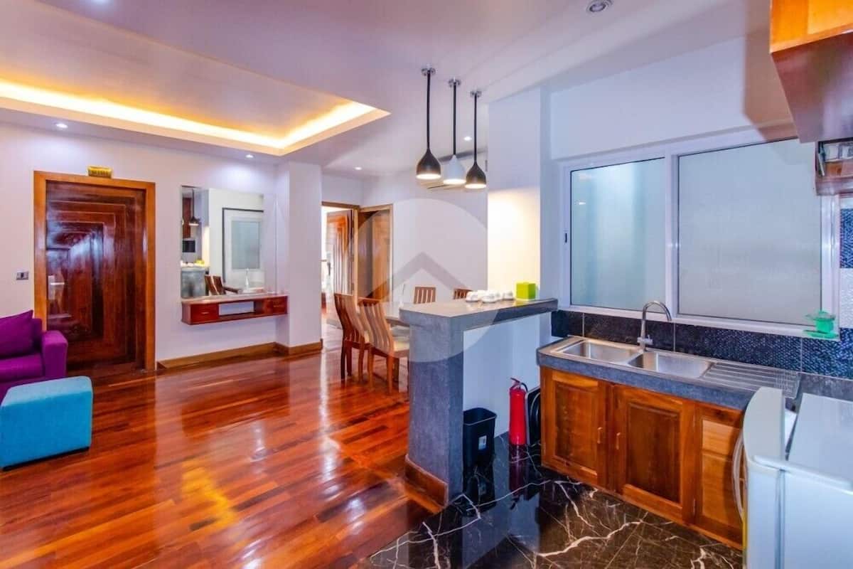 A modern kitchen with a marble countertop, wooden cabinets, and a built-in sink.