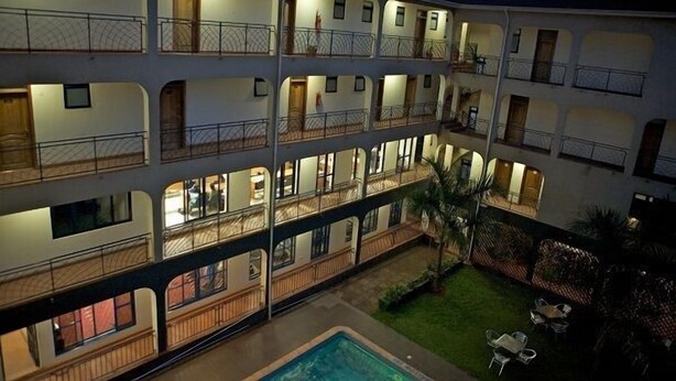 A multi-story hotel with balconies, a swimming pool, and outdoor seating. - Ivys Hotel (Kampala)