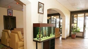 A lobby with a fish tank, seating area, and a potted plant. - Ivys Hotel (Kampala)