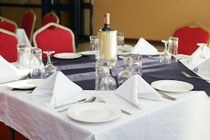 A table set for dining with white plates, silverware, and clear glassware. - Ivys Hotel (Kampala)