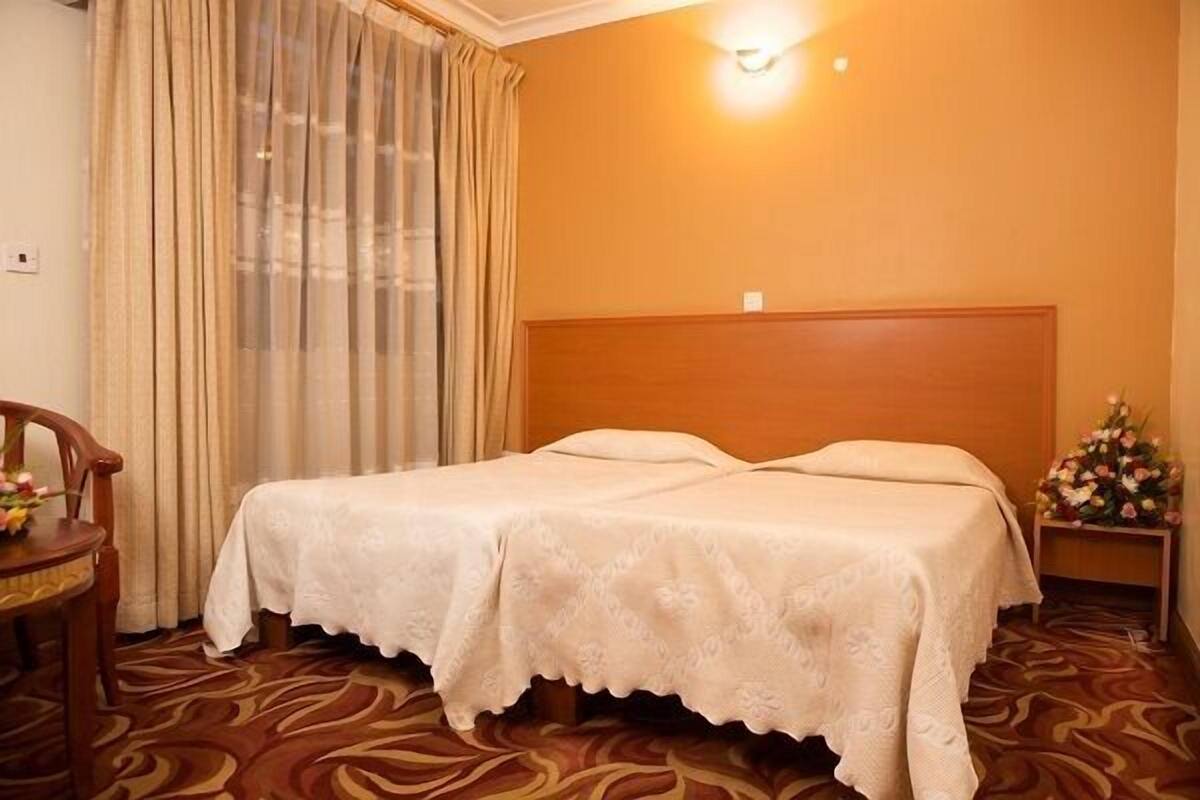 A hotel room with a bed, a nightstand with a lamp, and a chair.