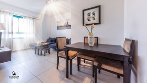 A modern living room with a dining table, sofa, and a framed picture on the wall.