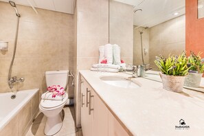 A modern bathroom with a bathtub, toilet, and sink.