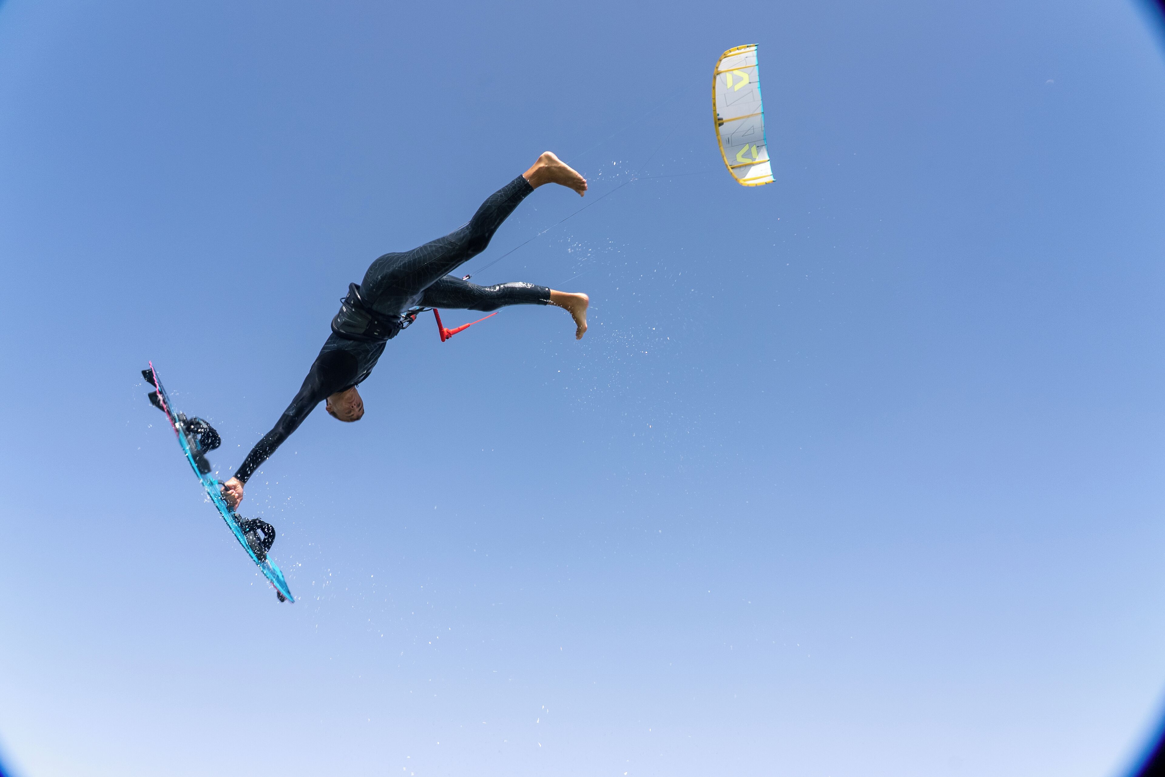 Una persona realizando un truco en una tabla de snowboard con un paracaídas.