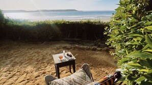 A beach chair with a hat, a small table with a bottle and a book, and a view of the ocean and distant land. - Pk 25 (Dakhla)