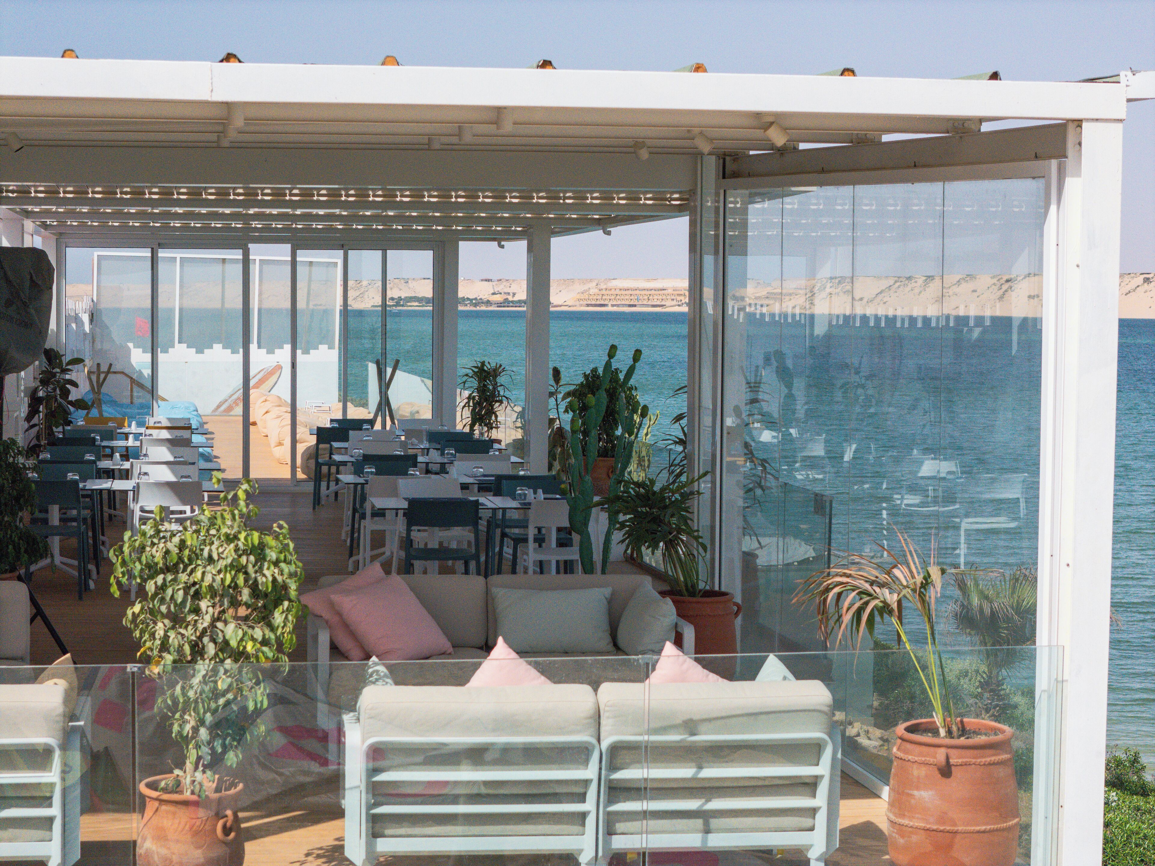 Terraza con asientos y mesas con vistas a una playa y al mar.