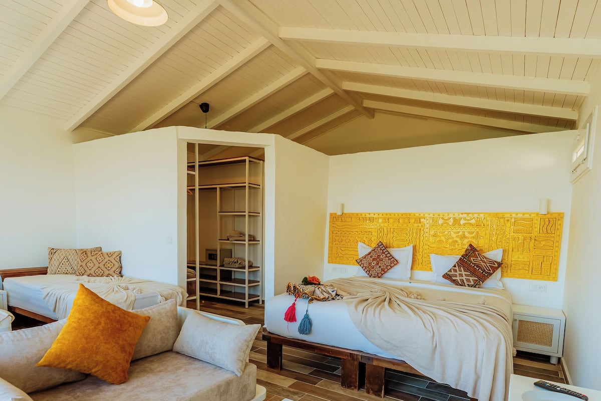 A room with a bed, a sofa, a table, and a wardrobe.