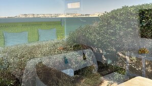 A modern interior with a high ceiling, pendant lighting, a large window, and a view of a natural landscape. - Pk 25 (Dakhla)