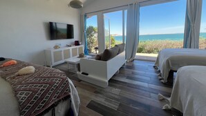 A modern bedroom with a large window, a flat-screen TV, a sofa, and two beds. - Pk 25 (Dakhla)